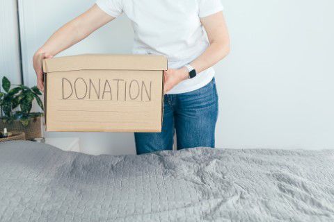 Woman preparing donation box of clothes for charity