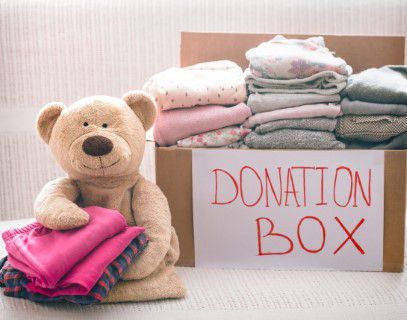 Box of clothes for donation next to a teddy bear